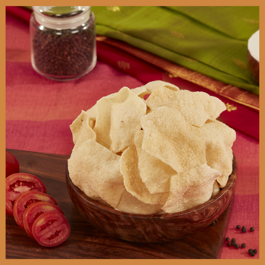 Malu's homemade tomato or Thakkali vadam snacks served in a wooden bowl with sliced tomatoes on the side
