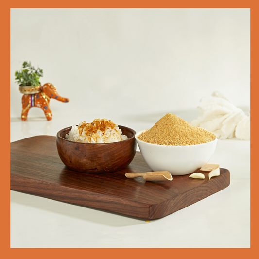 Malu's South Indian garlic paruppu podi served with rice on a wooden board with garlic cloves